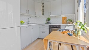 Une cuisine moderne avec des meubles blancs, une table en bois et une vue sur la ville par la fenêtre.