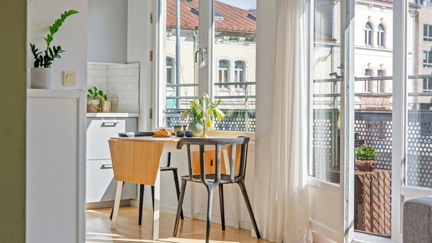 Une cuisine moderne avec un coin repas, de grandes fenêtres et une vue sur les immebles.