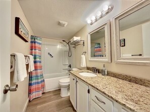 A bathroom with a shower, toilet, sink, and vanity.