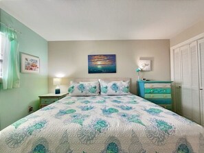 A bedroom with a bed, a nightstand, a dresser, a lamp, and a painting on the wall.