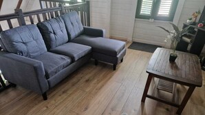 A grey sectional sofa and a wooden coffee table in a room with wooden flooring and a white wall.