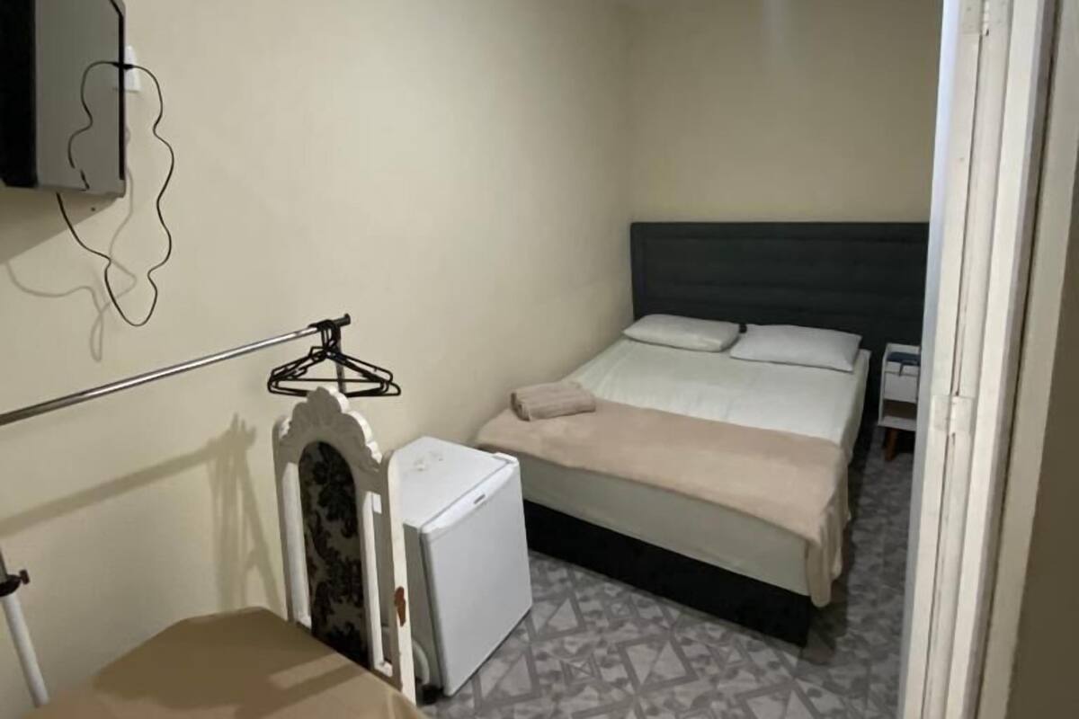Una habitación pequeña y limpia con cama, escritorio y silla.