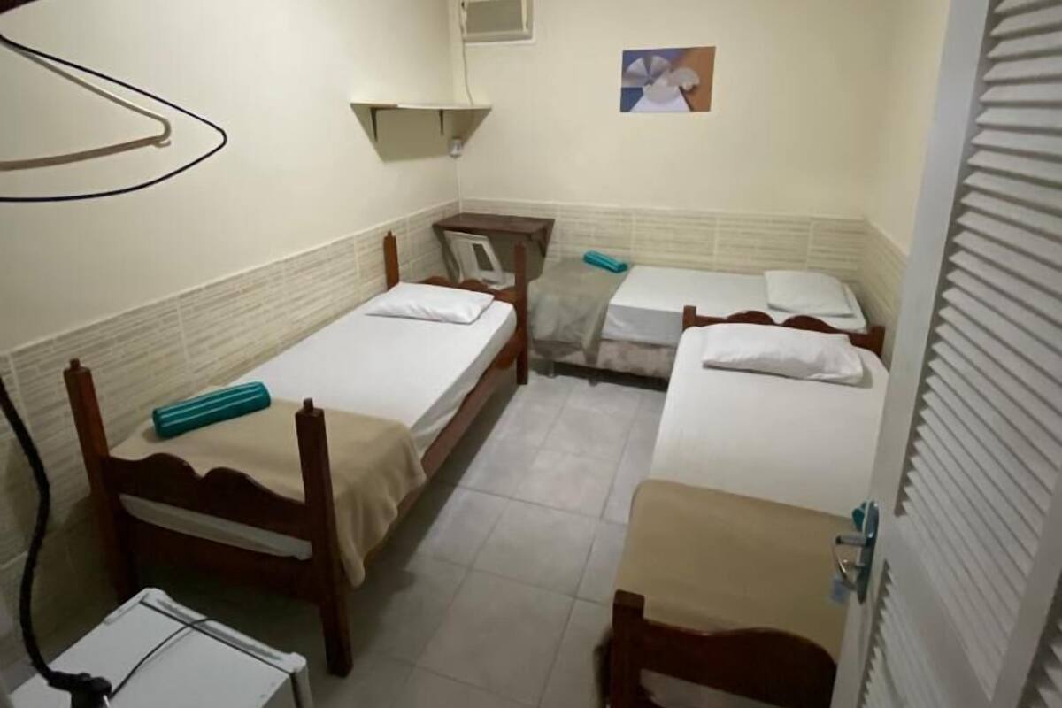 Una habitación pequeña y funcional con dos camas individuales, un escritorio y una silla.