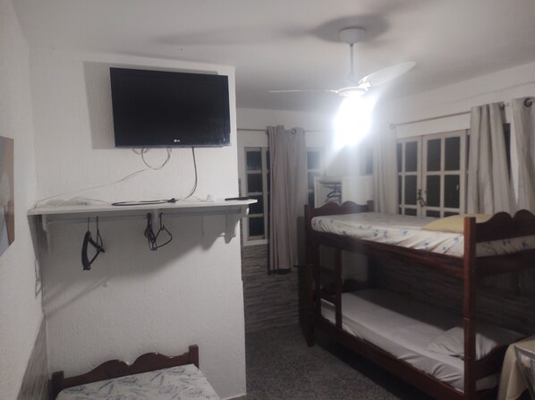 A room with a bunk bed, a desk with a flat-screen TV, a ceiling fan, and a window with curtains. - POUSADA NASCENTE DO SOL  (Macae)