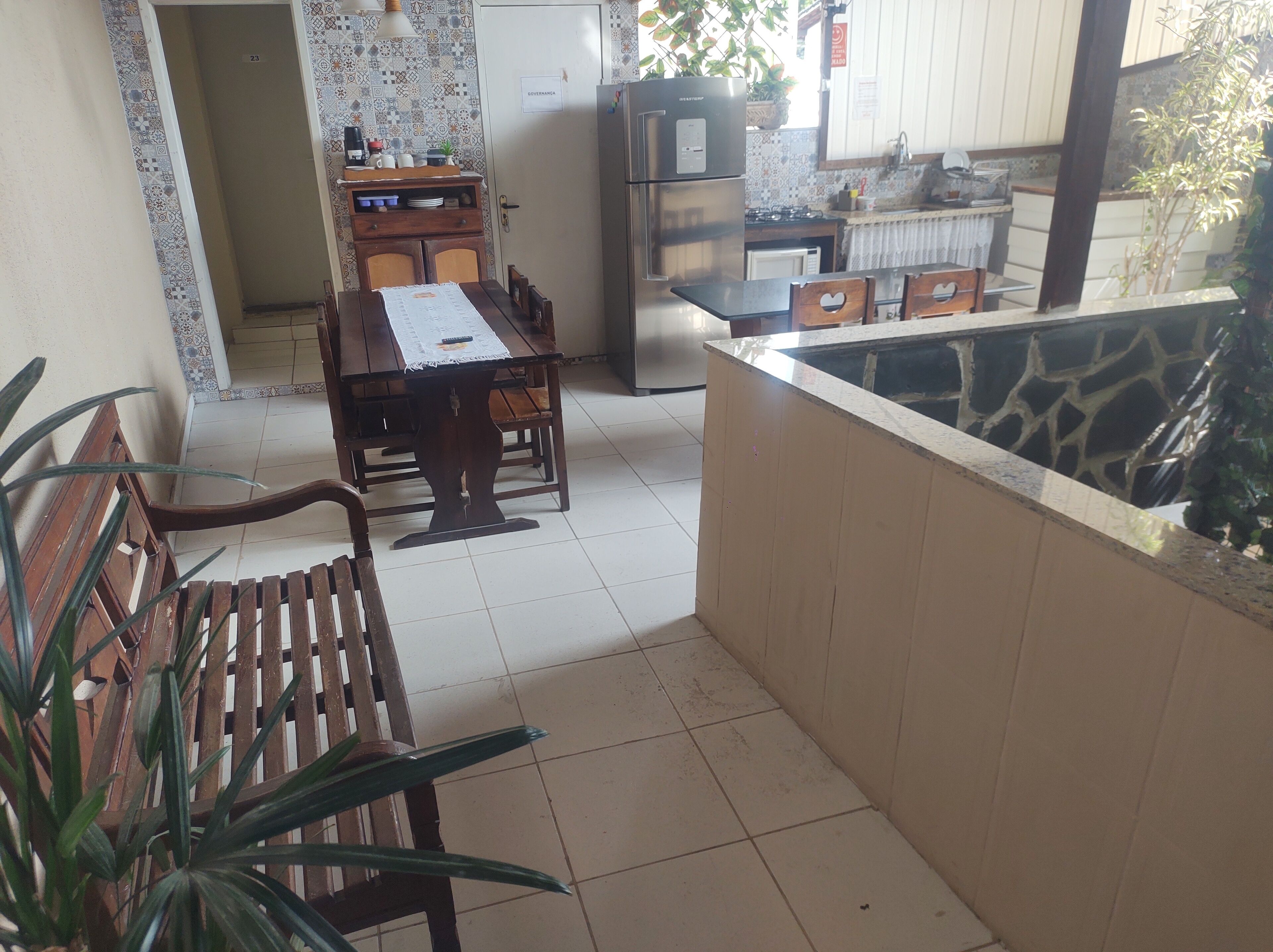 A dining area with a wooden table and chairs, a kitchen with a refrigerator and stove, and a tiled floor.