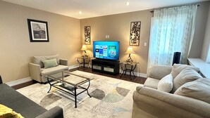 A living room with a flat-screen TV, two sofas, a coffee table, and decorative wall art.
