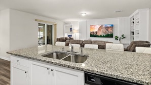 A modern kitchen with granite countertops, a built-in sink, and a dishwasher. - Private Pool 4BR | Sleeps 10 + Near Beach (Palm Coast)
