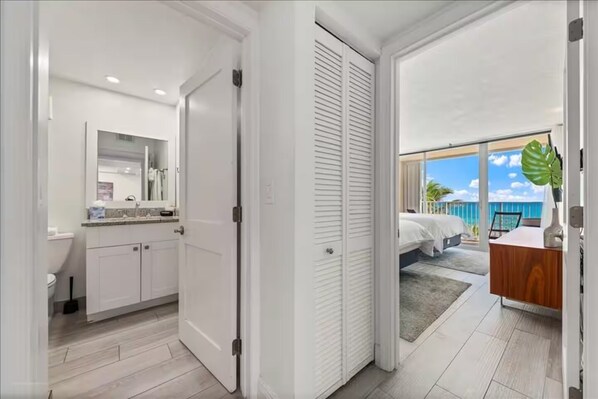 A modern hotel room with a bathroom, a balcony with a view, and a wooden dresser. - 404 On Hutchinson Island  (Jensen Beach)