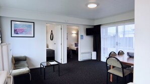Una camera d'albergo compatta con un letto, un tavolino, una sedia, una scrivania e una finestra.