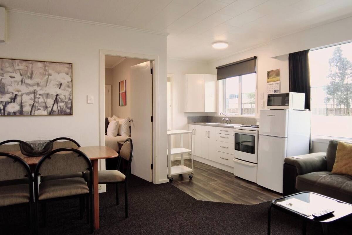 A compact living space with a kitchenette, a dining area, and a seating area with a sofa and a coffee table.