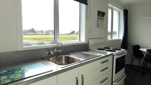Cucina con lavello, fornello e finestra vista su un prato.