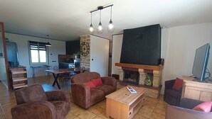 Ein Wohnzimmer mit Kamin, Essbereich und einer Küche im Hintergrund.