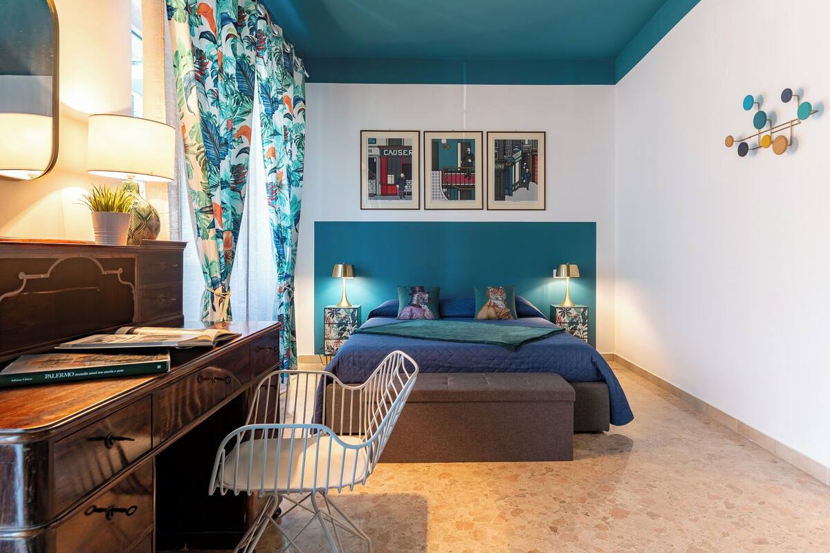 A bedroom with a bed, bedside tables, a desk, and a chair.