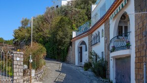 A narrow cobblestone street flanked by buildings with stone walls and tiled roofs. - Estate4home - Bonview suite (Massa Lubrense)