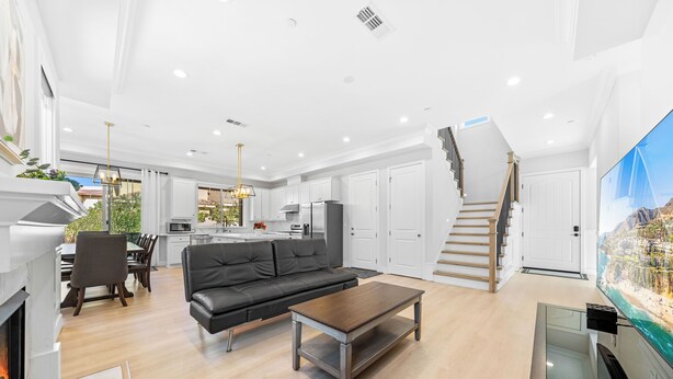 A modern living room with a fireplace, a black leather sofa, a wooden coffee table, and a large flat-screen TV. - 4 New Construction in 2024 luxury home 4B/4.5B (Temple City)