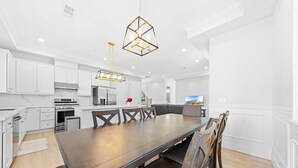 A modern kitchen with white cabinetry, a large dining table, and a unique geometric pendant light. - 4 New Construction in 2024 luxury home 4B/4.5B (Temple City)