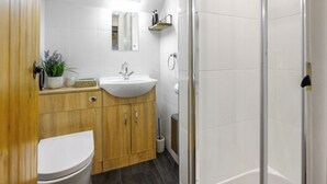 Un baño moderno con tocador de madera, lavabo blanco y cabina de ducha de vidrio.