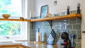 Una cocina con encimeras de madera, una cafetera y un juego de cuchillos.