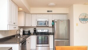 A kitchen with white cabinets, stainless steel appliances, a microwave, oven, and refrigerator.