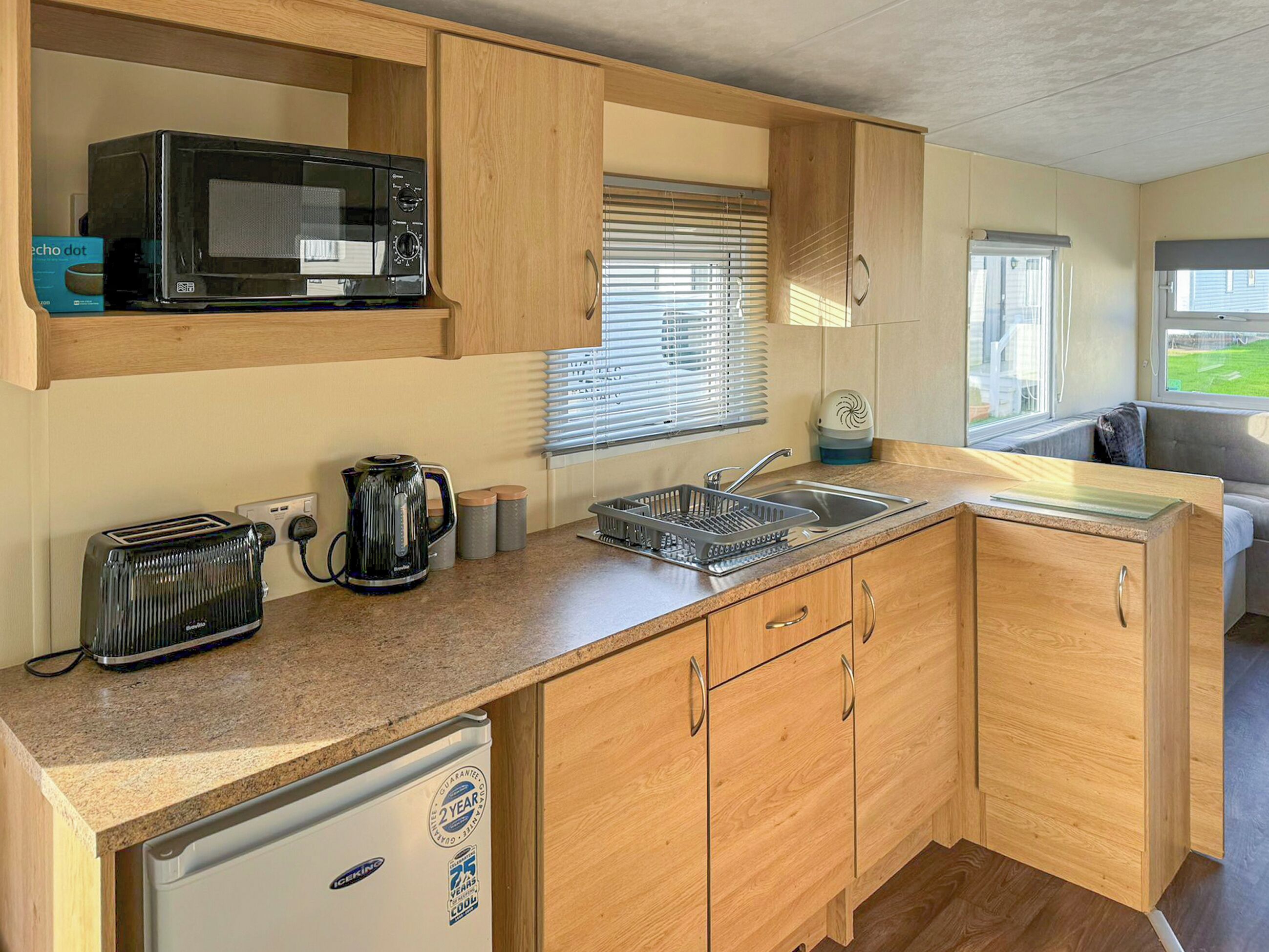 A compact kitchen with a microwave, toaster, kettle, and sink.