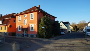 A street with a red building, a white van, and a blue building in the background. - Midgard vacation apartment in Sagenharz - Family apartment, 2 bedrooms & WLAN (Thale)
