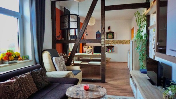 A living room with a sofa, a round coffee table, and a staircase leading to an upper level. - Midgard vacation apartment in Sagenharz - Family apartment, 2 bedrooms & WLAN (Thale)
