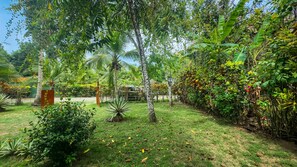A lush garden with various plants and trees, a wooden fence, and a pathway. - Casa Ylang Ayala, pool home minutes to the sand! (Palo Seco Beach, Parrita,)