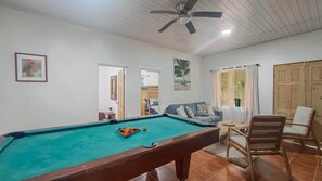 A pool table with balls, a ceiling fan, a sofa, a chair, and a door leading to another room. - Casa Ylang Ayala, pool home minutes to the sand! (Palo Seco Beach, Parrita,)