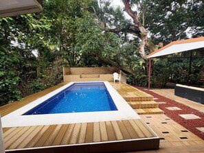 A rectangular swimming pool with a wooden deck surrounding it, a white chair, and a wooden bench. - Casa Ylang Ayala, pool home minutes to the sand! (Palo Seco Beach, Parrita,)