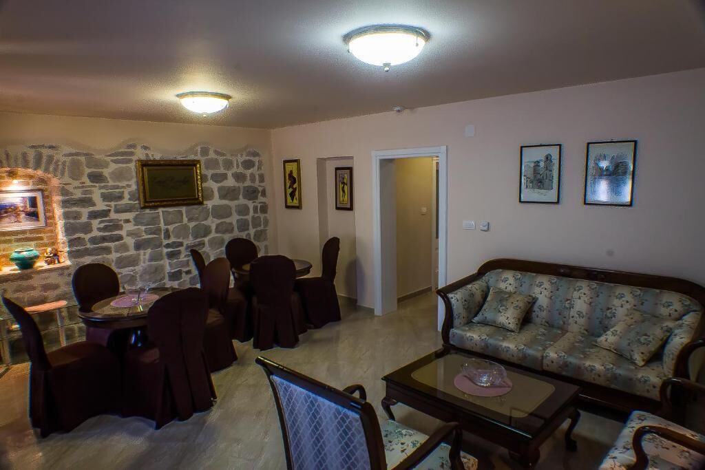 A living room with a stone wall, a dining area with a table and chairs, a sofa, and framed pictures on the walls.
