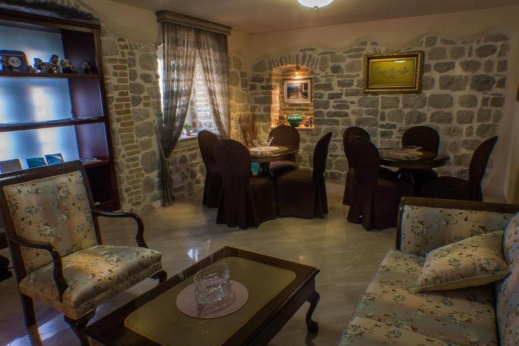 A cozy living room with a stone wall, a dining table with chairs, a sofa, and a coffee table.