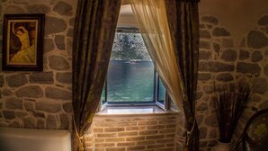 Una stanza con parete in pietra, una finestra, tende e un quadro incorniciato.