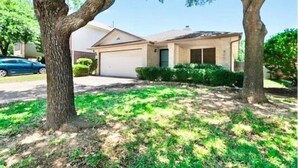 A residential house with a garage, a driveway, and a lawn with trees. - Round Rock - Austin Hideaway (Round Rock)