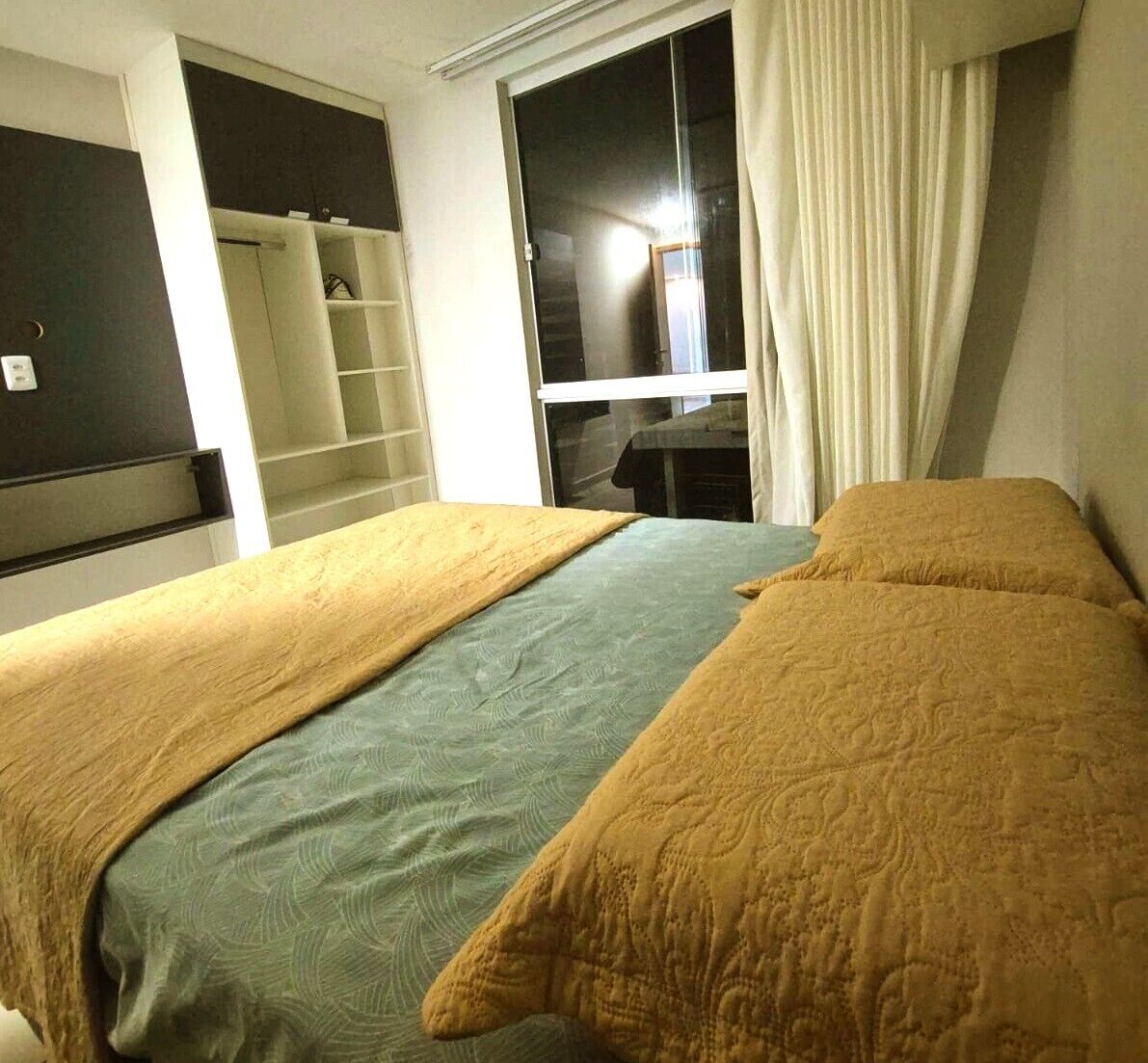 Ein Schlafzimmer mit zwei Betten, einem Kleiderschrank und einem Fenster mit Vorhängen.