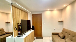 Een moderne woonkamer met een televisie, bank en een houten roomdivider.