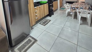 Een moderne keuken met houten kastjes, een roestvrijstalen koelkast, een zwarte afzuigkap en een eethoek met een tafel en stoelen.