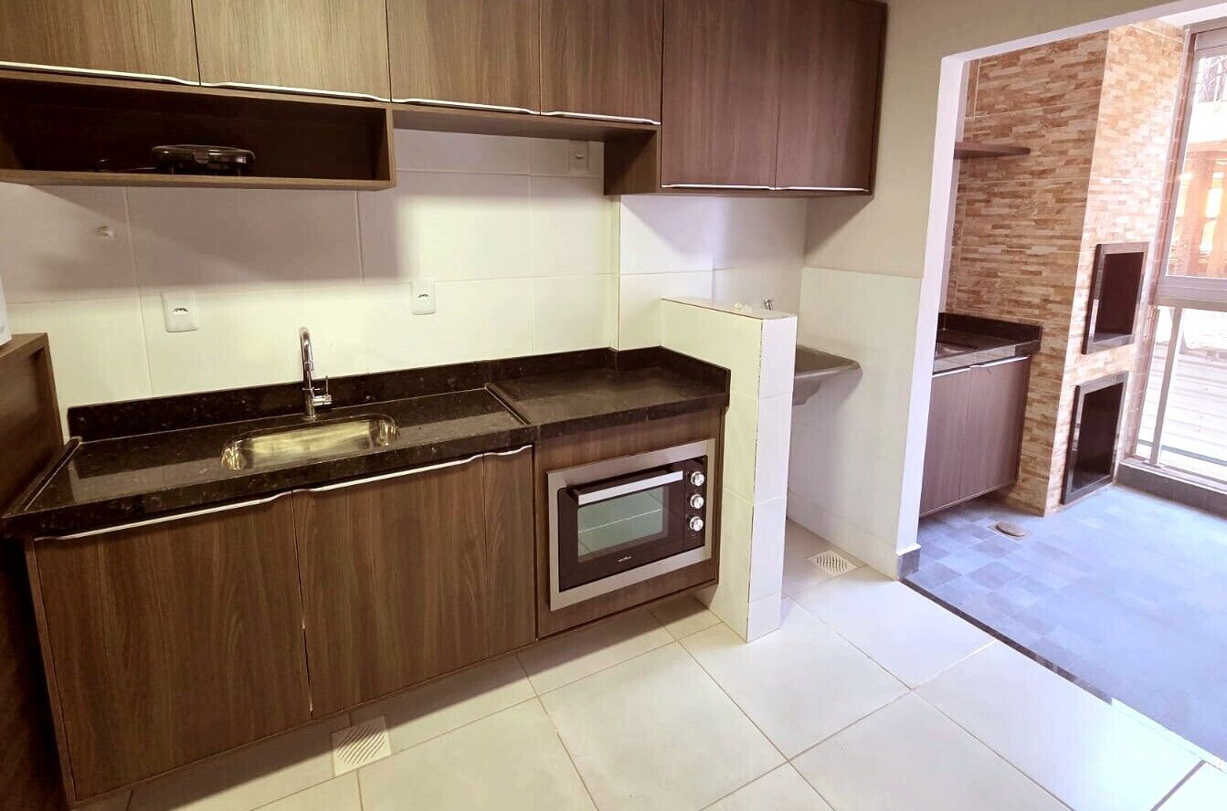 A modern kitchen with dark wood cabinets, a built-in oven, and a countertop with a sink.