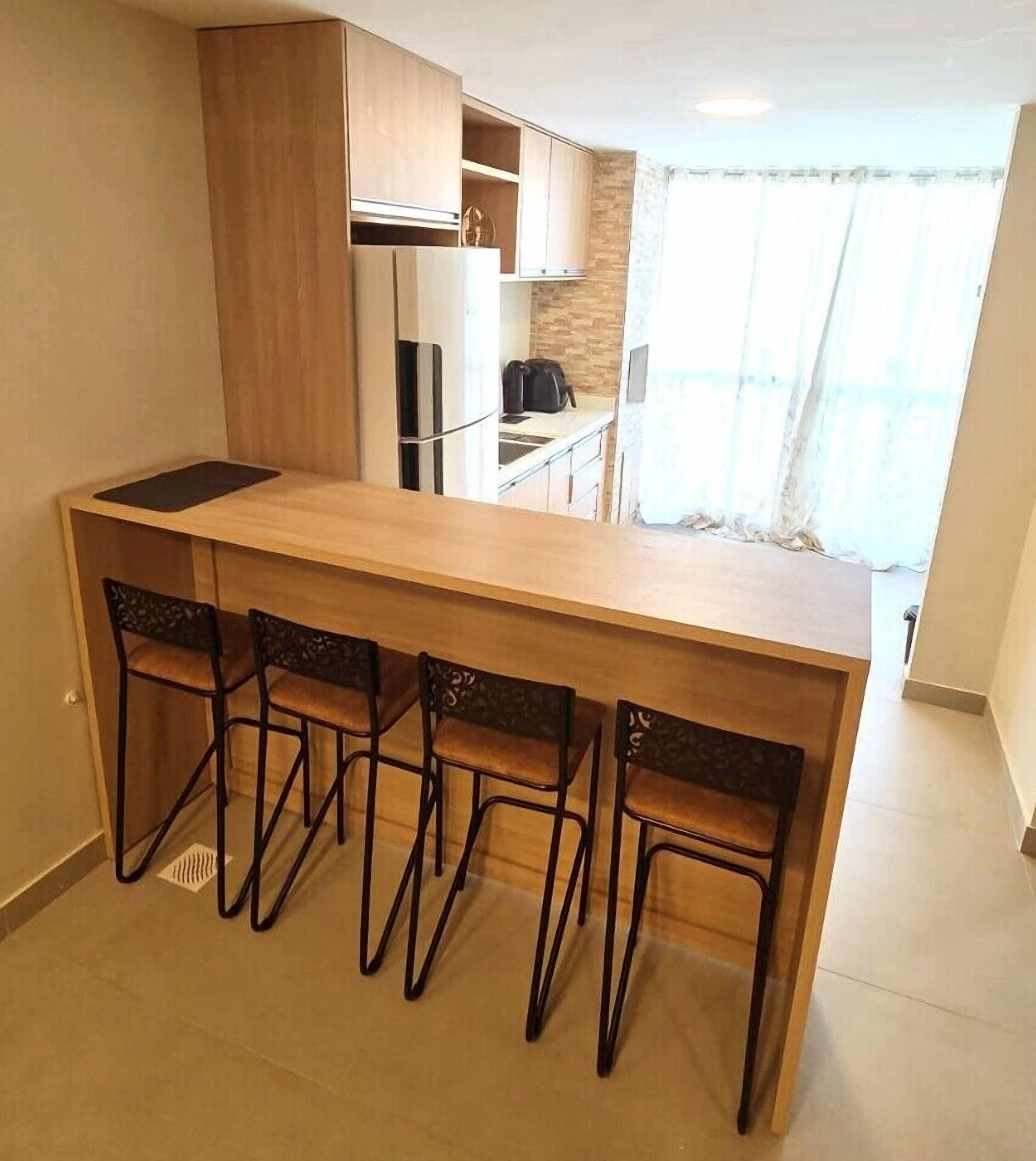 A compact kitchen with a central island, four chairs, and a refrigerator.