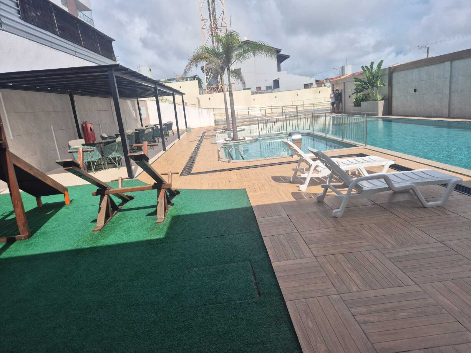 Área de piscina no terraço, com espreguiçadeiras, uma piscina pequena e um espaço de estar coberto.