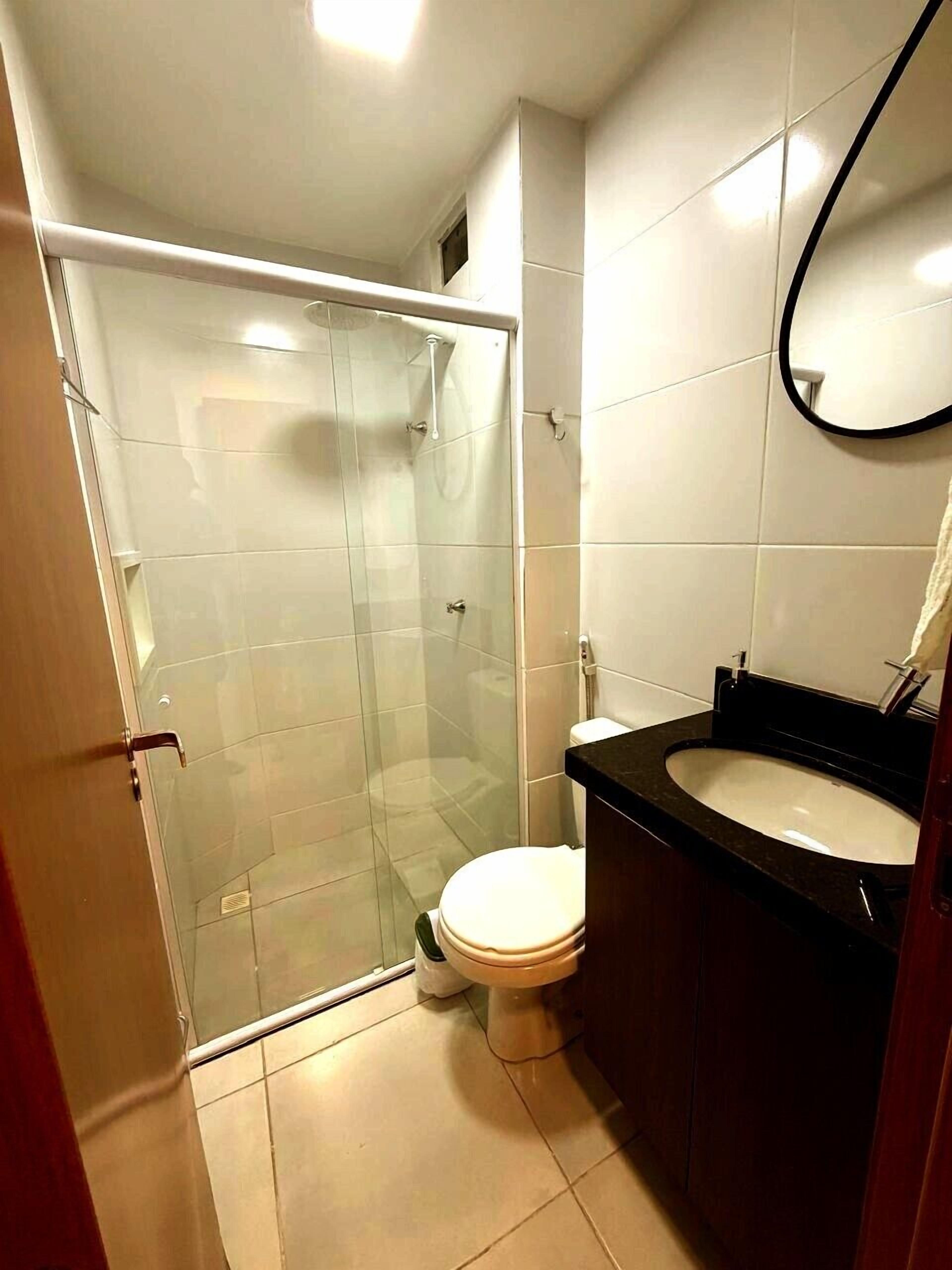 A modern bathroom with a glass-enclosed shower, a white toilet, and a black sink.
