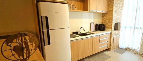 A compact kitchen with a refrigerator, sink, and wooden cabinets.