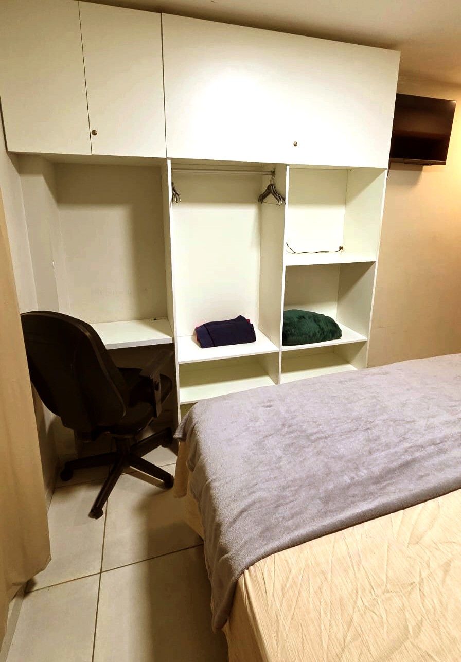 A bedroom with a bed, a desk, and a wardrobe.