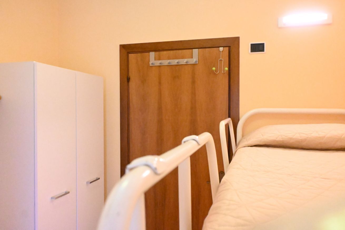 Une pièce avec une porte en bois, une armoire blanche et un lit avec du linge de lit blanc.