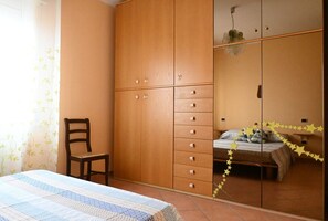 A bedroom with a bed, wooden wardrobe, and a chair.