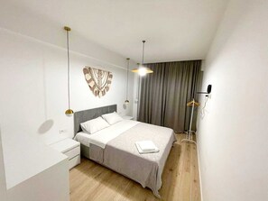 Ein modernes Schlafzimmer mit einem Bett, Nachttischen, einer Wanddekoration aus Makramee und einer Stehlampe.