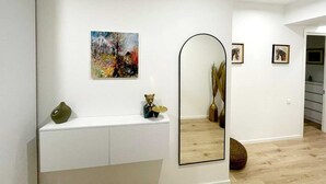 Un interior moderno con una consola blanca, un espejo grande y un cuadro abstracto.