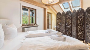 A bedroom with a large bed, a window, and a decorative wooden partition.