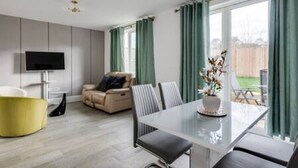 Una sala de estar moderna con una mesa de comedor, sofá y televisor.