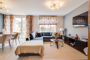Ein modernes Wohnzimmer mit Sofa, Esstisch und Bett.