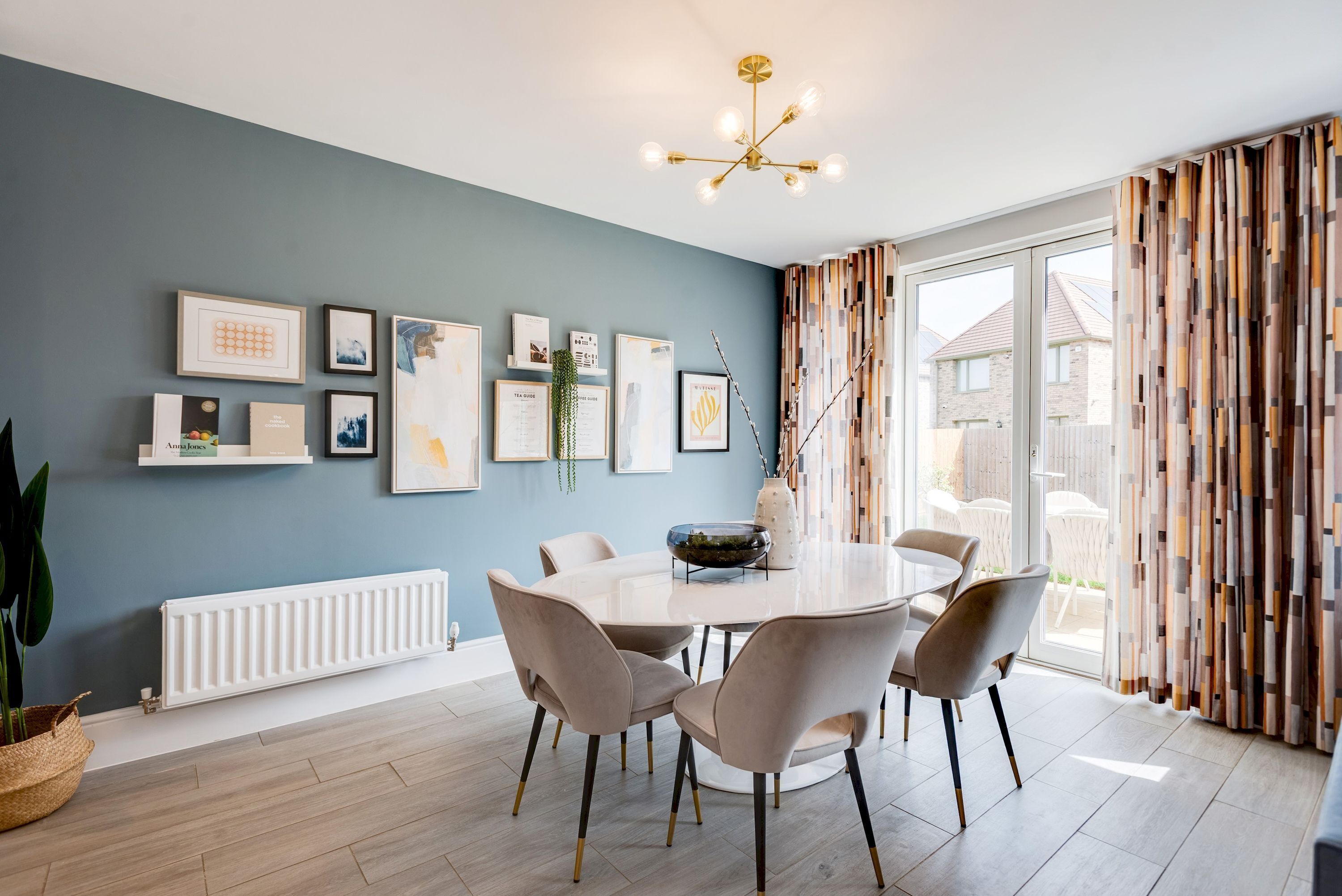 Een eetruimte met een ronde tafel, stoelen en een lijst met kunstwerk aan de muur.